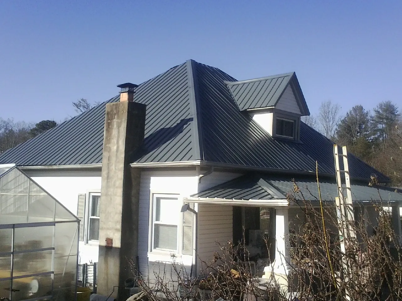 Dark blue standing seam metal roof on a white farmhouse with dormer — Slate & Tile Roof Repair by Roofing Brothers in Rittman