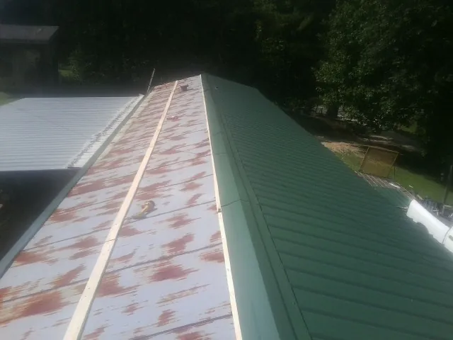 Old rusted panels beside newly installed green metal roofing — Wind Damage Roof Repair by Roofing Brothers in Rittman