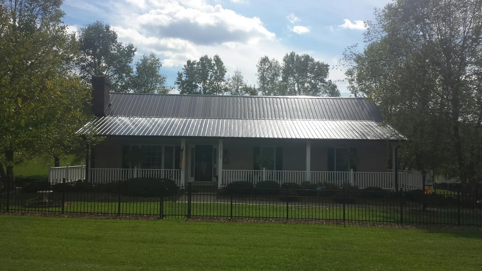 Gray metal roof on a brick ranch with a full width front porch — Gutter Guard Installation work by our crew in Rittman