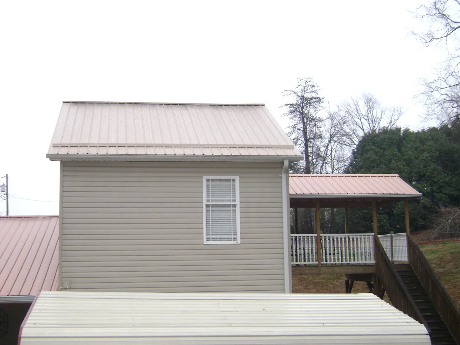 Tan metal roofs on a two story addition and attached porch, from a Roof Replacement job in Rittman