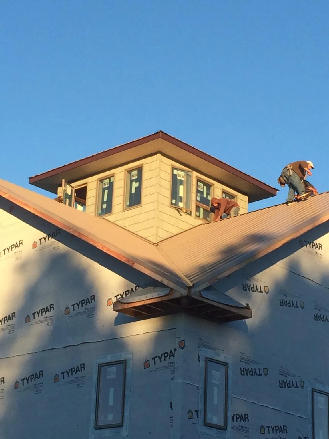 Roofers working around a rooftop cupola on a new metal roof at sunset — Roof Waterproofing in Rittman by Roofing Brothers